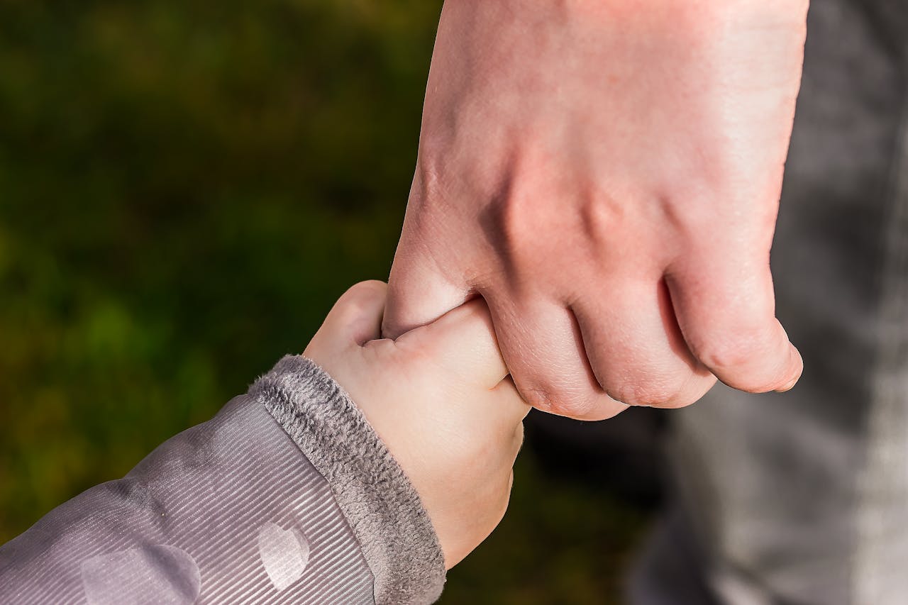 heros-img A close-up of a child and parent holding hands in a park, symbolizing love and trust.